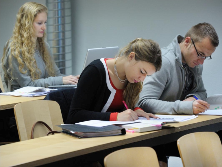 Personen machen sich Notizen während Vorlesung