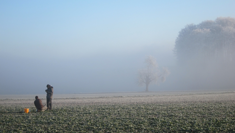Zwei Bodenkundler auf einem winterlichen Agrarfeld, Nebel im Hintergrund